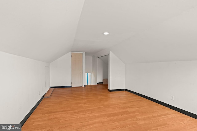 additional living space with vaulted ceiling, light wood finished floors, and baseboards