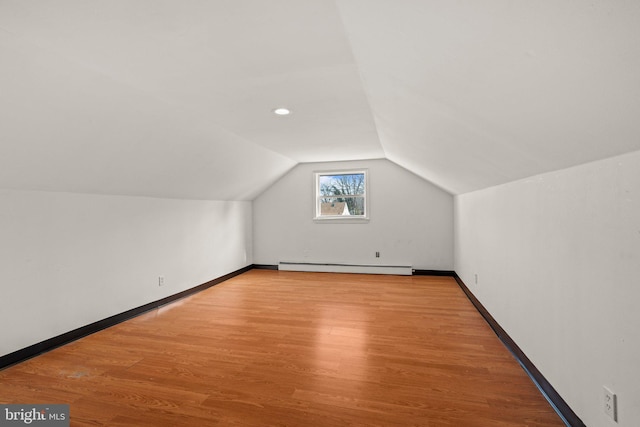 additional living space with lofted ceiling, baseboards, baseboard heating, and wood finished floors