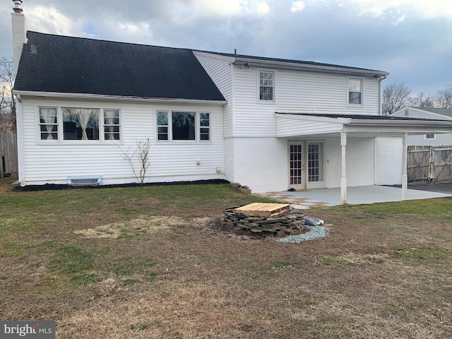 back of property featuring a lawn, a patio, a chimney, fence, and french doors