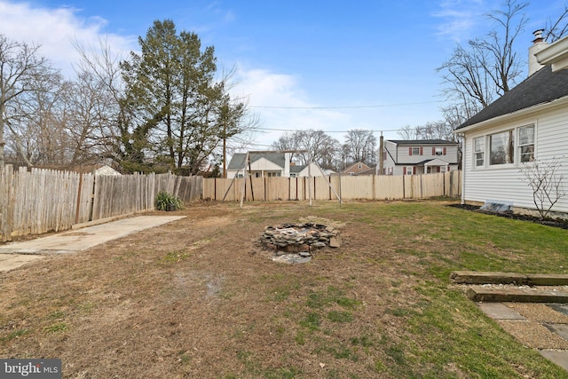 view of yard with a fenced backyard and a fire pit