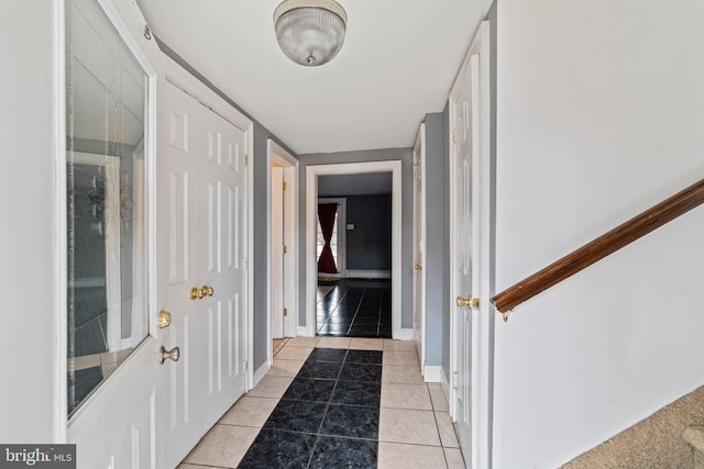 doorway with light tile patterned flooring and baseboards