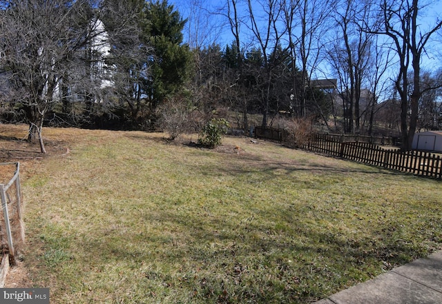 view of yard featuring fence, an outdoor structure, and a shed