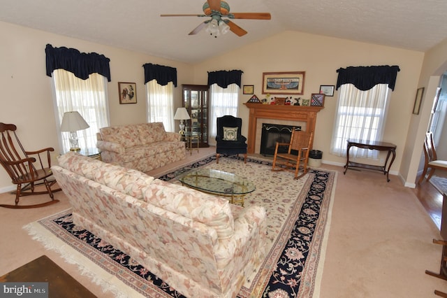 carpeted living area with lofted ceiling, a tiled fireplace, a wealth of natural light, and baseboards