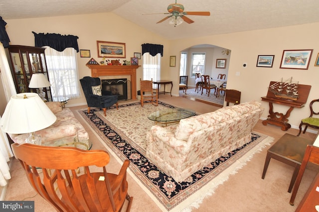 living room featuring arched walkways, vaulted ceiling, a tiled fireplace, and a healthy amount of sunlight