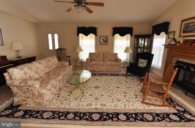 living room featuring lofted ceiling, a ceiling fan, and a tile fireplace