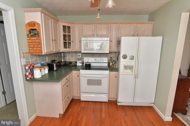 kitchen with dark countertops, white appliances, backsplash, and wood finished floors