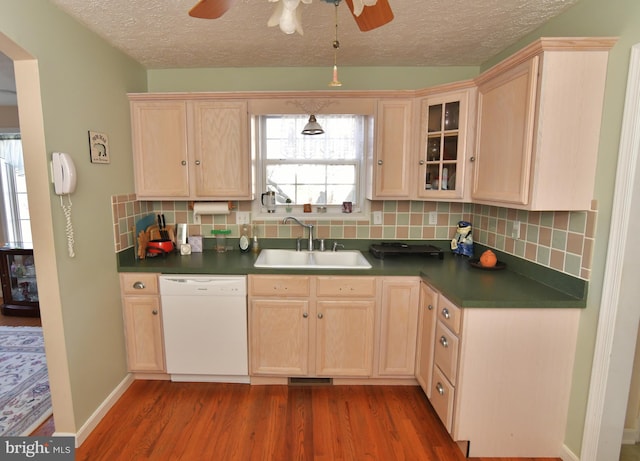 kitchen with wood finished floors, white dishwasher, a sink, and light brown cabinetry