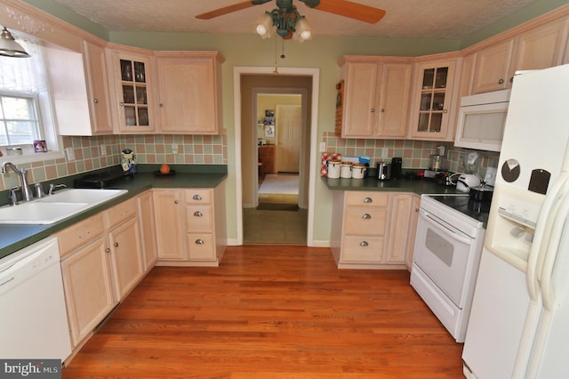 kitchen featuring white appliances, glass insert cabinets, light wood-type flooring, light brown cabinets, and a sink