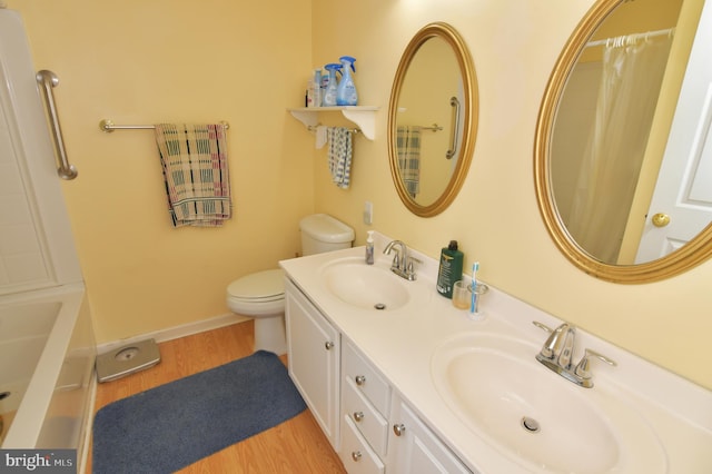 full bath with toilet, curtained shower, a sink, and wood finished floors