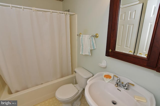 bathroom featuring toilet, shower / bath combo with shower curtain, and a sink