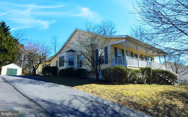 view of home's exterior featuring covered porch, aphalt driveway, and an outdoor structure