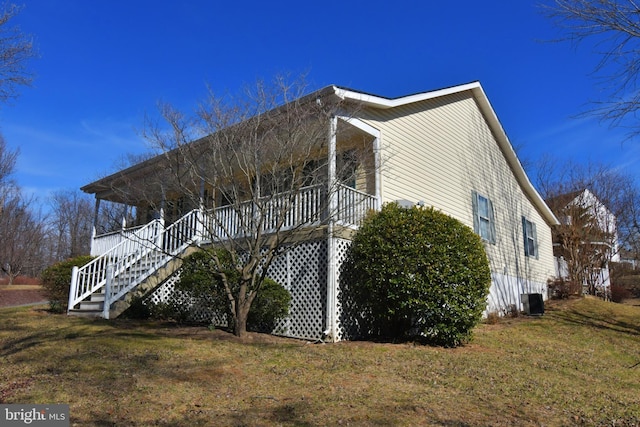 view of side of property with stairs and a lawn