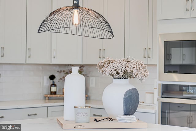 room details with light stone counters, oven, white cabinets, built in microwave, and tasteful backsplash