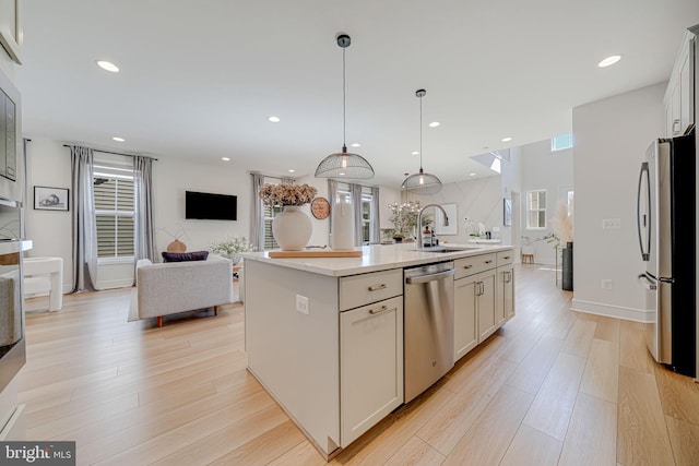 kitchen featuring light wood-style floors, stainless steel appliances, a sink, and open floor plan