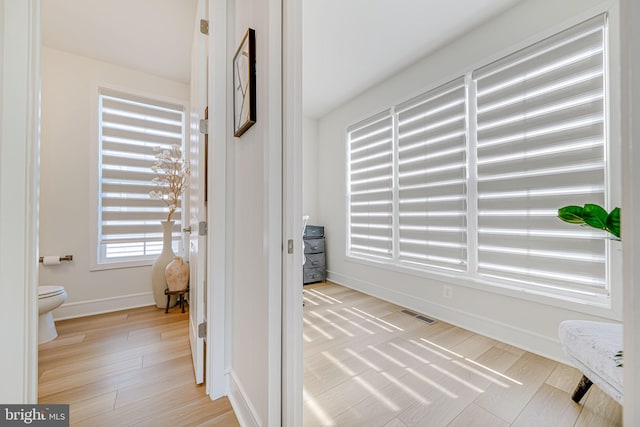 corridor featuring light wood-style floors, visible vents, and baseboards