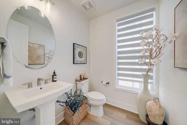 bathroom with toilet, baseboards, visible vents, and wood finished floors