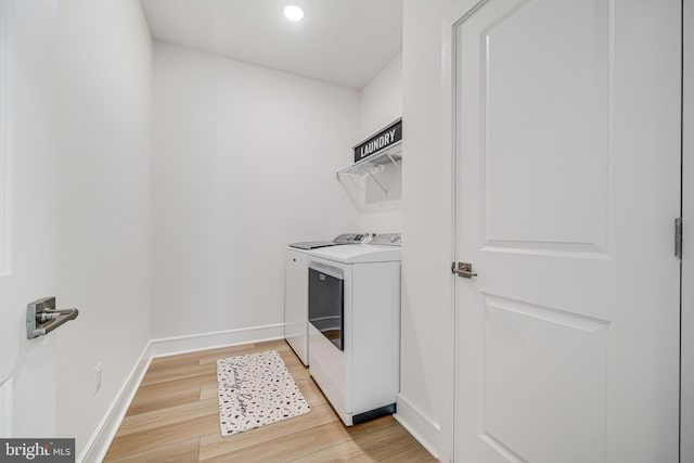 laundry area with laundry area, washer and clothes dryer, light wood-type flooring, and baseboards