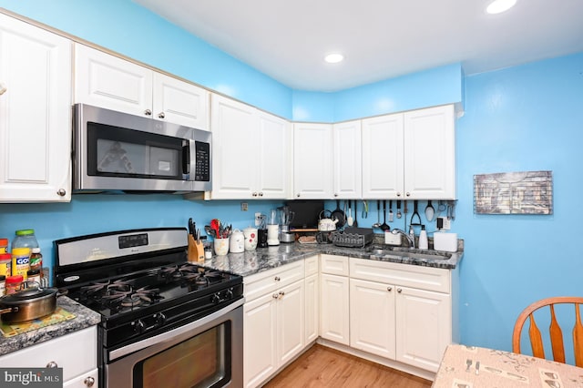 kitchen with light wood-style flooring, recessed lighting, a sink, white cabinetry, and appliances with stainless steel finishes