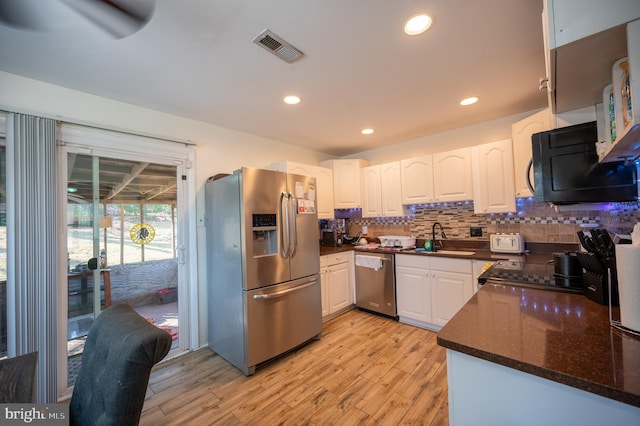 kitchen with stainless steel appliances, a sink, white cabinetry, visible vents, and decorative backsplash