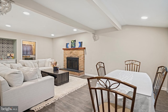 living area with beam ceiling, recessed lighting, dark wood-type flooring, a brick fireplace, and baseboards