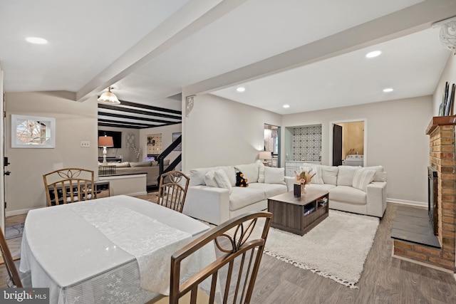 dining space featuring beam ceiling, recessed lighting, a brick fireplace, wood finished floors, and baseboards