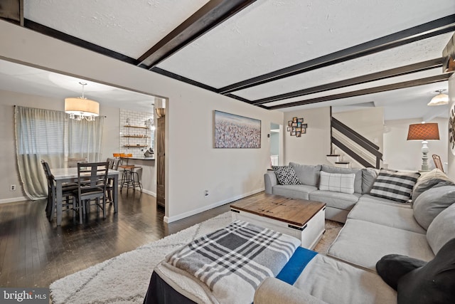 living room featuring stairway, a textured ceiling, beamed ceiling, baseboards, and hardwood / wood-style flooring