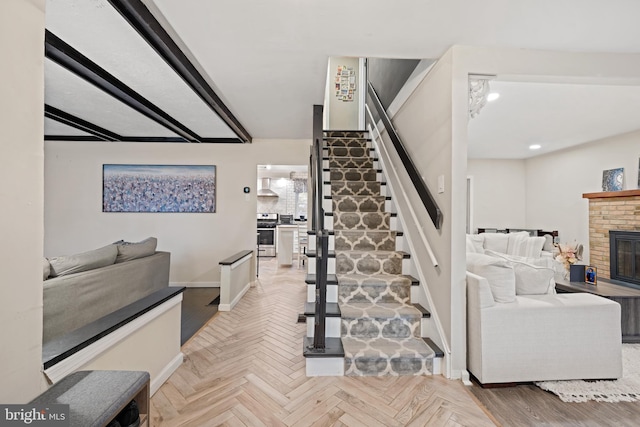 stairway featuring a brick fireplace and baseboards