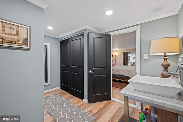 interior space featuring light wood-style floors, recessed lighting, a sink, and crown molding