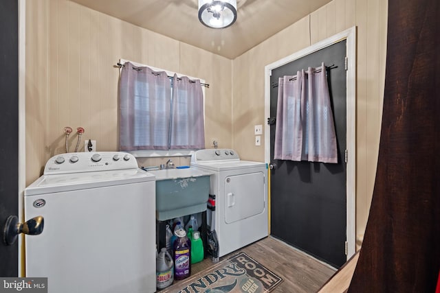 laundry area featuring a sink, laundry area, separate washer and dryer, and wood finished floors