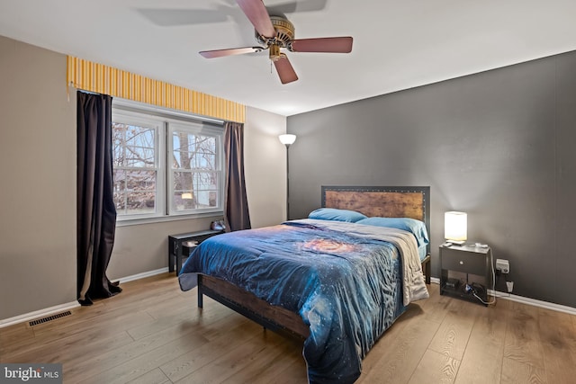 bedroom with baseboards, visible vents, ceiling fan, and wood finished floors