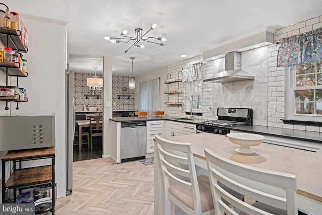 kitchen featuring wall chimney exhaust hood, decorative backsplash, stainless steel appliances, and a sink