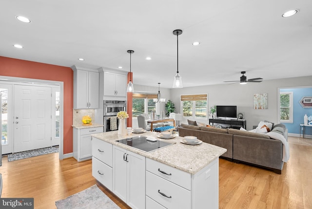 kitchen featuring white cabinetry, a center island, light wood-style floors, and black electric cooktop