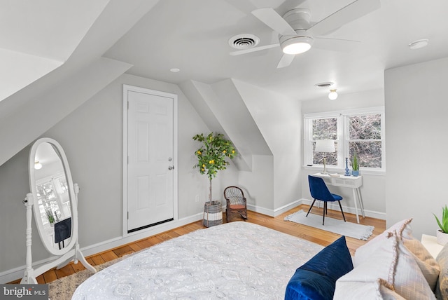 bedroom with visible vents, lofted ceiling, baseboards, and wood finished floors