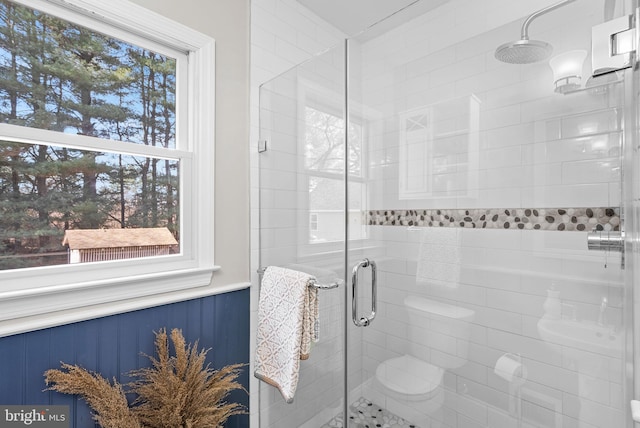 bathroom featuring a wainscoted wall and a stall shower