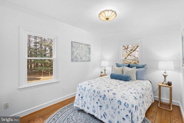 bedroom with ornamental molding, baseboards, and hardwood / wood-style flooring