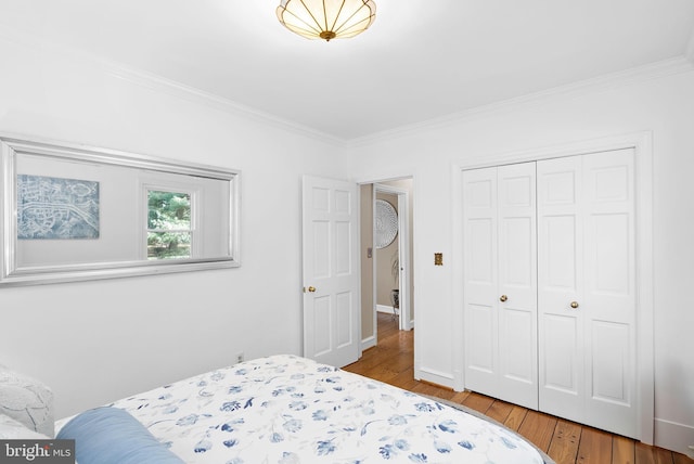 bedroom with wood finished floors, a closet, and ornamental molding