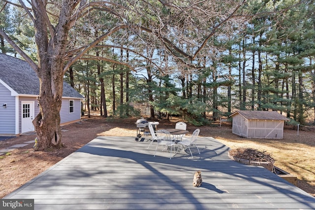 wooden terrace featuring a storage shed and an outbuilding