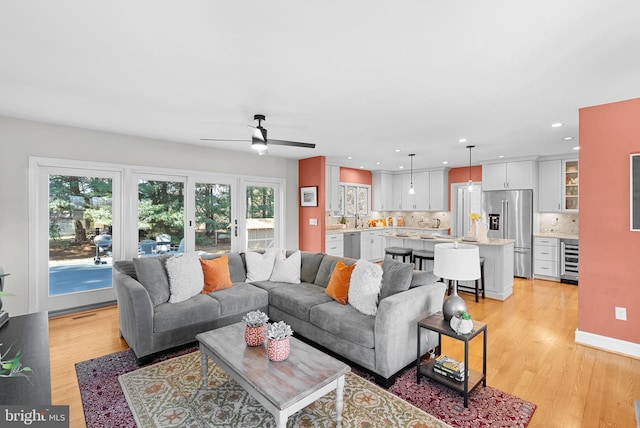 living area featuring recessed lighting, beverage cooler, ceiling fan, and light wood finished floors