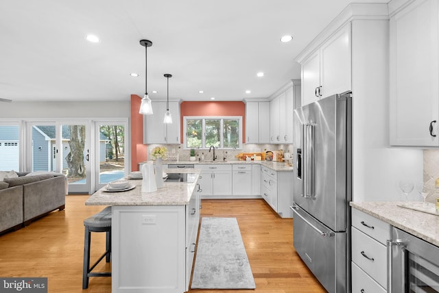 kitchen with beverage cooler, a sink, high end refrigerator, a kitchen breakfast bar, and open floor plan