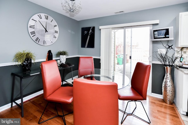 dining room with baseboards, visible vents, wood finished floors, and a chandelier