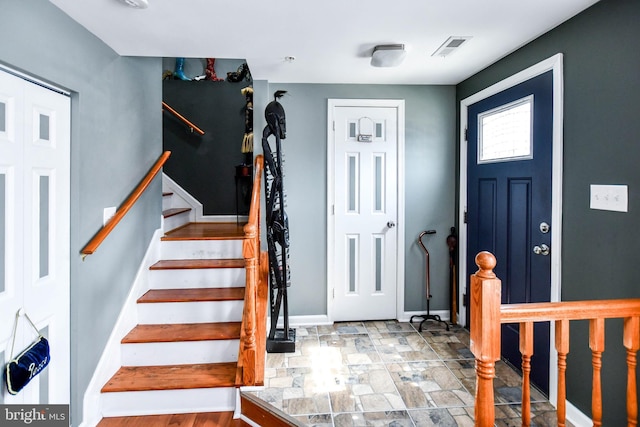 foyer entrance with stairs, visible vents, stone finish flooring, and baseboards