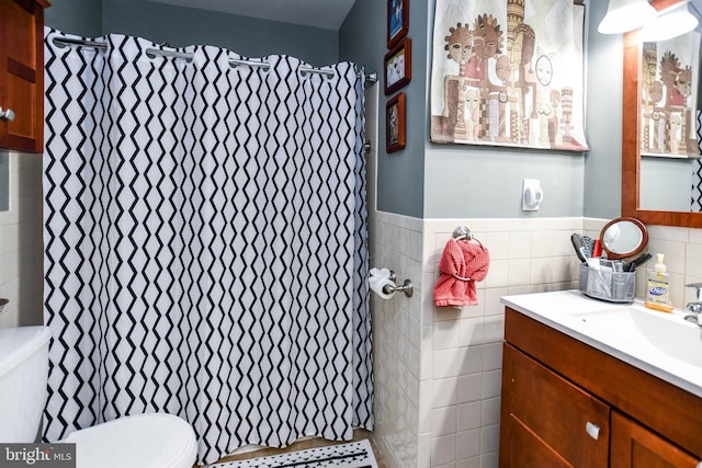 bathroom featuring tile walls, a wainscoted wall, toilet, and vanity