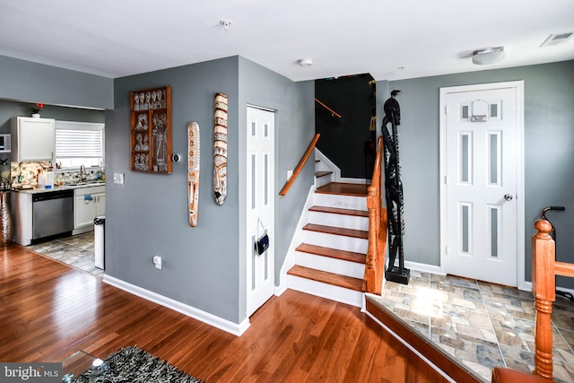 staircase featuring wood finished floors, baseboards, and visible vents