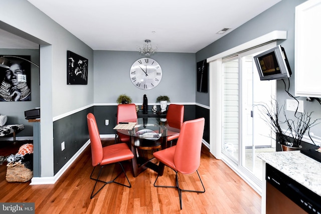 dining space featuring light wood finished floors, baseboards, and visible vents