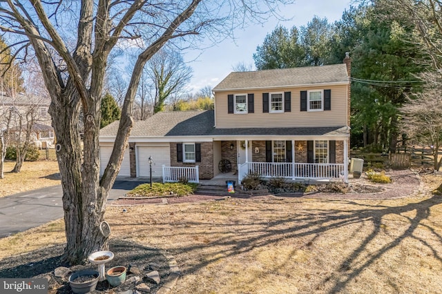 view of front of house with aphalt driveway, brick siding, a chimney, a porch, and an attached garage