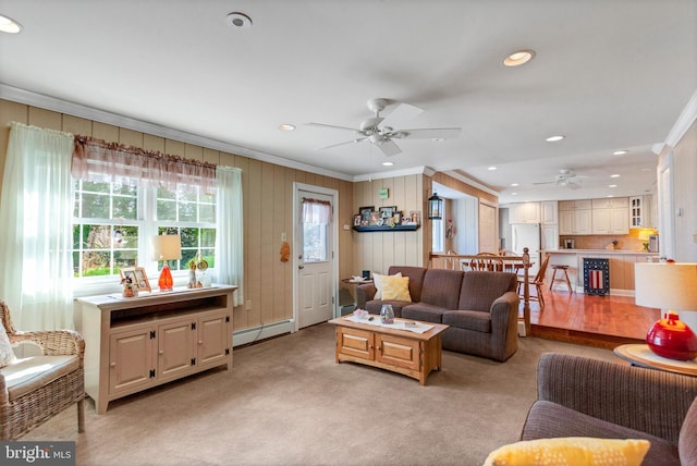 living room with a baseboard heating unit, light carpet, crown molding, and a ceiling fan