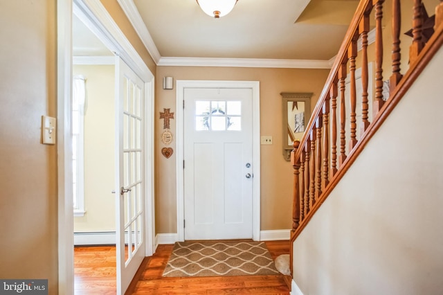 entryway with baseboards, a baseboard radiator, ornamental molding, and wood finished floors