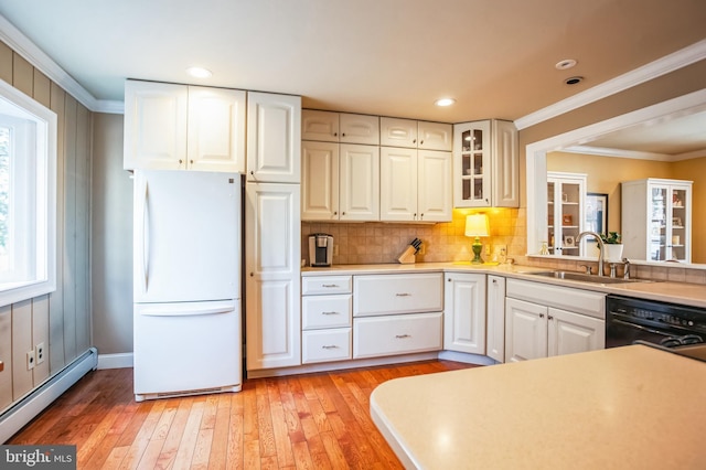 kitchen featuring black dishwasher, baseboard heating, ornamental molding, freestanding refrigerator, and a sink