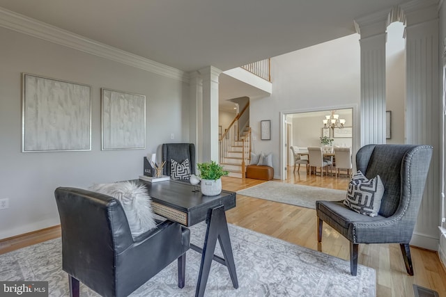 sitting room featuring wood finished floors, visible vents, stairs, decorative columns, and crown molding