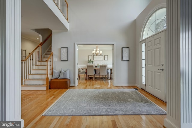 foyer featuring stairs, a towering ceiling, baseboards, and wood finished floors